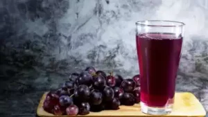 "Glass of purple grape juice with ice cubes and fresh grapes on the side, representing a refreshing and healthy South Indian Beverage."